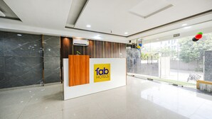 A hotel reception area with a modern design, featuring a reception desk, a logo, and a view of the outside. - Fabhotel Radiant Blu (Noida)