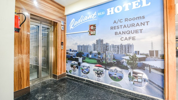 A hotel interior with a large poster advertising A/C rooms, a restaurant, a banquet, and a cafe. - Fabhotel Radiant Blu (Noida)