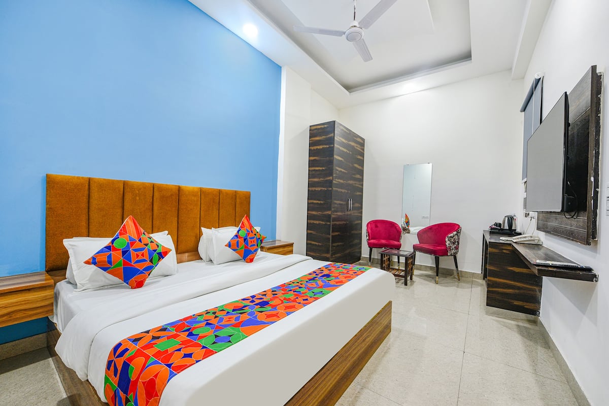 A hotel room with a bed, a desk, a chair, a wardrobe, and a television.