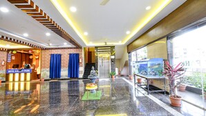 A hotel lobby with a reception desk, a statue, and a fish tank.