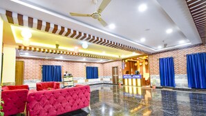 A hotel lobby with a reception desk, red sofas, and a polished marble floor.