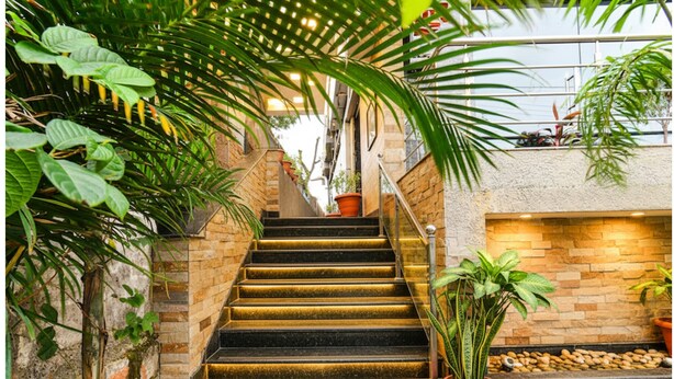 A staircase with stone walls, potted plants, and a brick wall with a built-in fireplace.