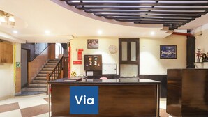 A reception area with a reception desk labeled "Via," a staircase, and a clock on the wall. - Fabexpress Rajdeep Palace (New Delhi)