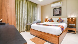 Een moderne hotelkamer met een houten bed, een bureau, een stoel en een groot raam met gordijnen.