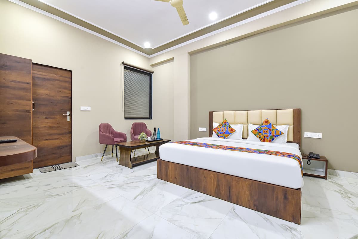 Ein modernes Hotelzimmer mit einem großen Bett, einem Holzkopfstück und einem Schreibtisch mit Stühlen.