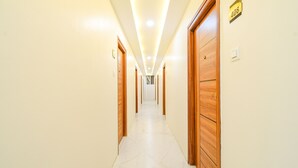 A hotel hallway with wooden doors, numbered room signs, and a tiled floor. - Fabhotel Ssr Ikon Suites (Hyderabad)