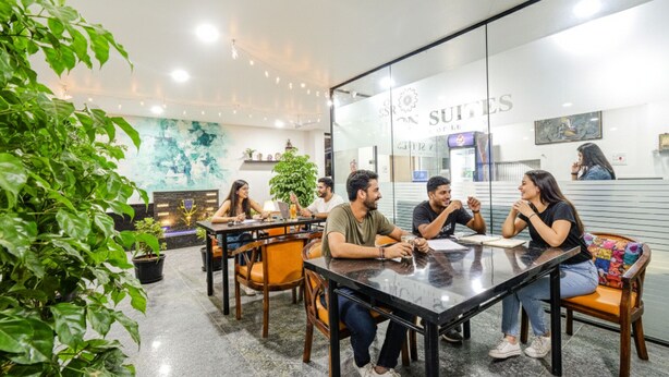 A conference room with a glass partition, wooden chairs, and a table. - Fabhotel Ssr Ikon Suites (Hyderabad)