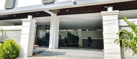 A modern building with a covered entrance, large pillars, and potted plants.