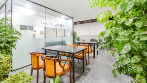 A conference room with glass walls, wooden chairs, and a table. - Fabhotel Ssr Ikon Suites (Hyderabad)