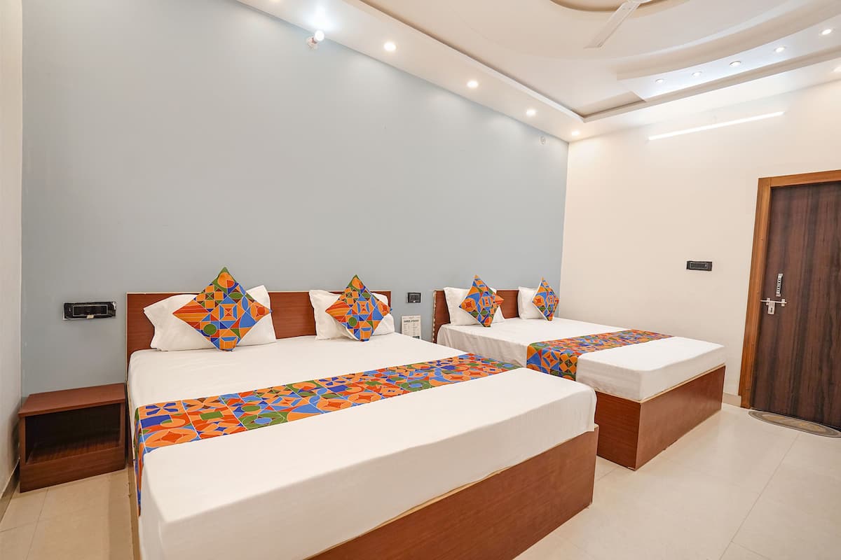 Een hotelkamer met twee bedden, elk voorzien van een bedspreider met een patroon, houten hoofdeinden en een klein nachtkastje.