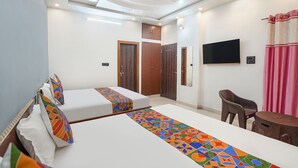 A hotel room with two beds, a TV, a ceiling fan, and a small table. - Fabhotel Shree Radha Ashtami Seva Ashram (Mathura)