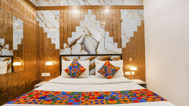 A modern hotel room with a marble-patterned headboard, wooden paneling, and a colorful geometric bedspread. - Fabhotel Golden Key (New Delhi)