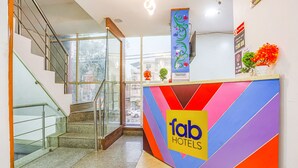 A hotel reception area with a colorful reception desk, a staircase, and a view of the outside. - Fabhotel Golden Key (New Delhi)