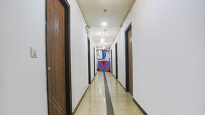 A hallway with a marble floor, wooden doors, and a colorful wall decoration at the end. - Fabhotel Golden Key (New Delhi)
