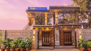 A hotel entrance with a sign reading "fabHOTELS," a modern design with a glass facade, and a brick wall with potted plants. - Fabexpress Ramayana Premium (Faizabad)