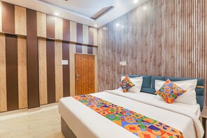 A hotel room with a bed, a wooden wardrobe, and a wall with vertical wooden slats. - Fabexpress Ramayana Premium (Faizabad)