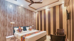 A modern bedroom with a bed, a nightstand, a chair, and a ceiling fan. - Fabexpress Ramayana Premium (Faizabad)