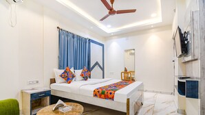 A modern hotel room with a bed, a desk, a chair, a TV, and a ceiling fan. - Fabhotel City Star (Bidhannagar)