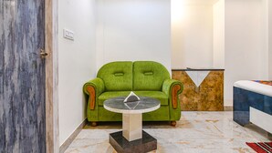 A room with a green sofa, a small round table, a reception desk, and a bed. - Fabhotel City Star (Bidhannagar)