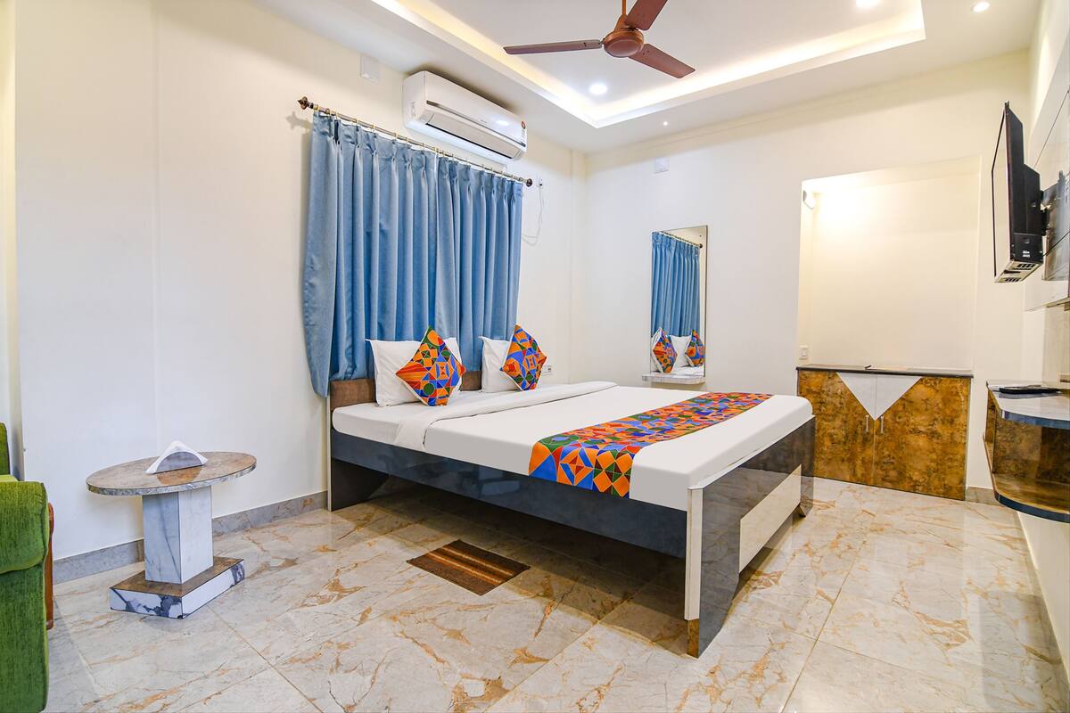 A modern bedroom with a bed, air conditioning unit, ceiling fan, and a small table.