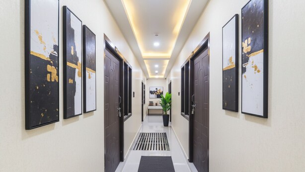 A hotel hallway with framed artwork on the walls, a potted plant, and a reception desk in the distance. - Fabhotel Awadh Inn - 600 m from Ram mandir (Ayodhya)