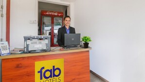 A reception desk with a laptop, a printer, and a QR code sign. - Fabexpress Shree Siya Raman (Ayodhya)