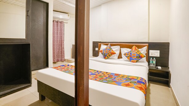 Une chambre d’hôtel avec un lit, une table de chevet et un miroir.