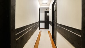 Un couloir d’hôtel avec un sol carrelé, des murs blancs et des murs ornés d’un motif noir et blanc.