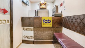 Un espace d’accueil avec une enseigne indiquant « fab hotels », un ventilateur de plafond, une caméra de surveillance et un banc.