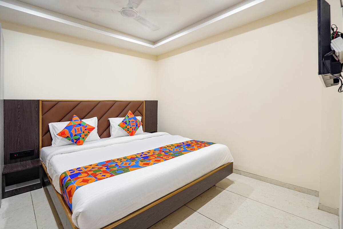Une chambre d’hôtel équipée d’un lit, d’une table de chevet, d’un ventilateur de plafond et d’un climatiseur fixé au mur.