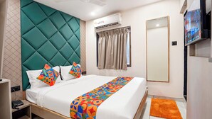 A hotel room with a bed, a TV, an air conditioning unit, and a window with curtains. - Fabhotel 7 Star I (Surat)