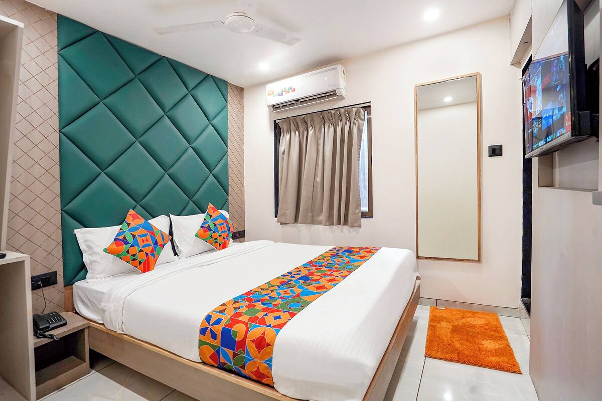 Une chambre d’hôtel équipée d’un lit, d’une télévision, d’un système de climatisation et d’une fenêtre avec des rideaux.