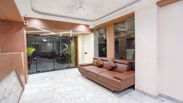 A modern lobby with a leather sofa, marble flooring, and glass doors leading to a dining area. - Fabhotel 7 Star I (Surat)