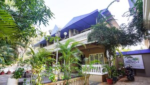 A two-story building with a balcony, potted plants, and a motorcycle parked outside.