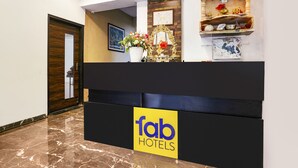 A reception desk with a 'fab hotels' sign, a framed picture, and a decorative shelf with items.