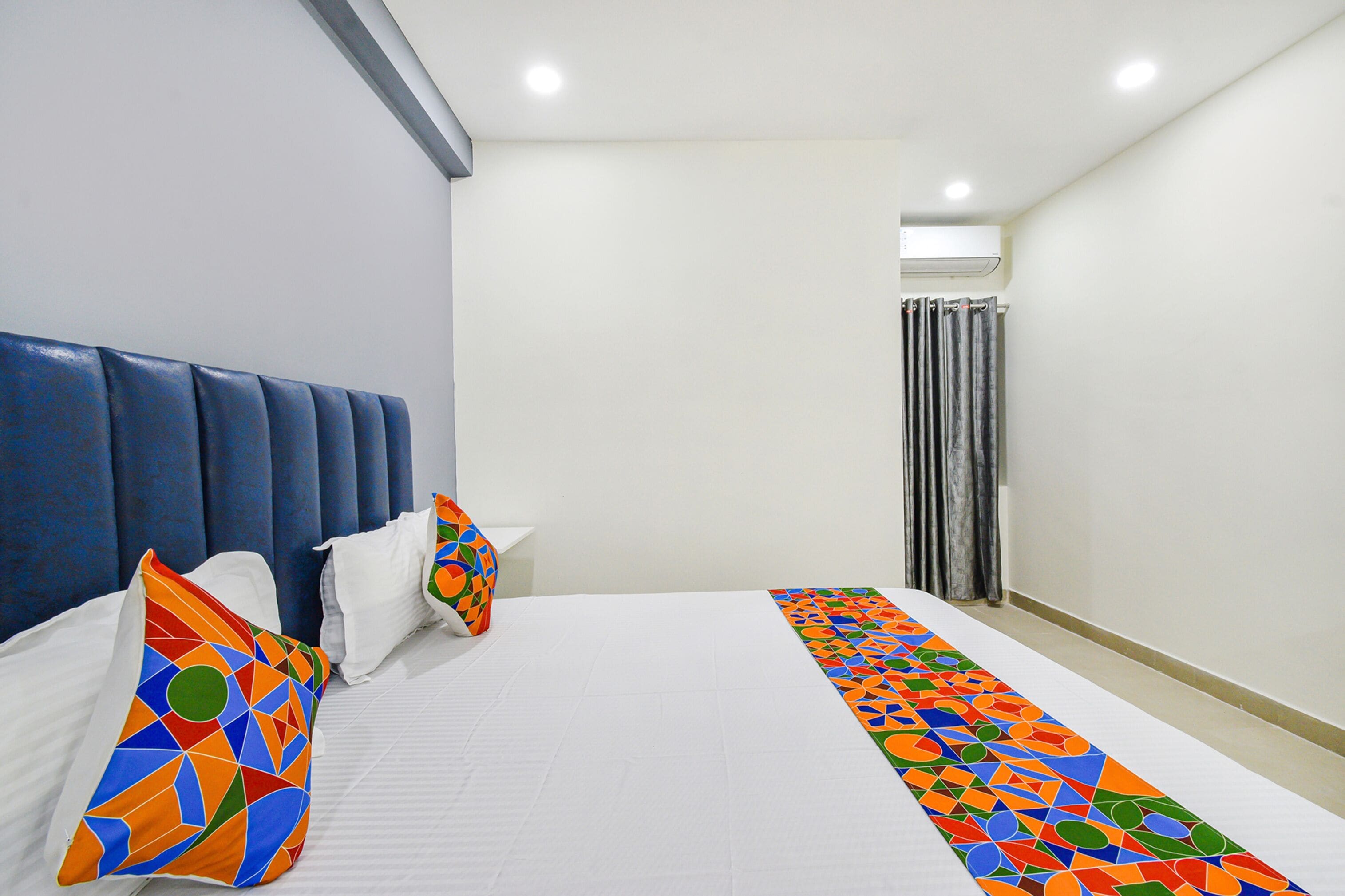 Une chambre d’hôtel avec un grand lit, une tête de lit bleue et un tapis coloré.
