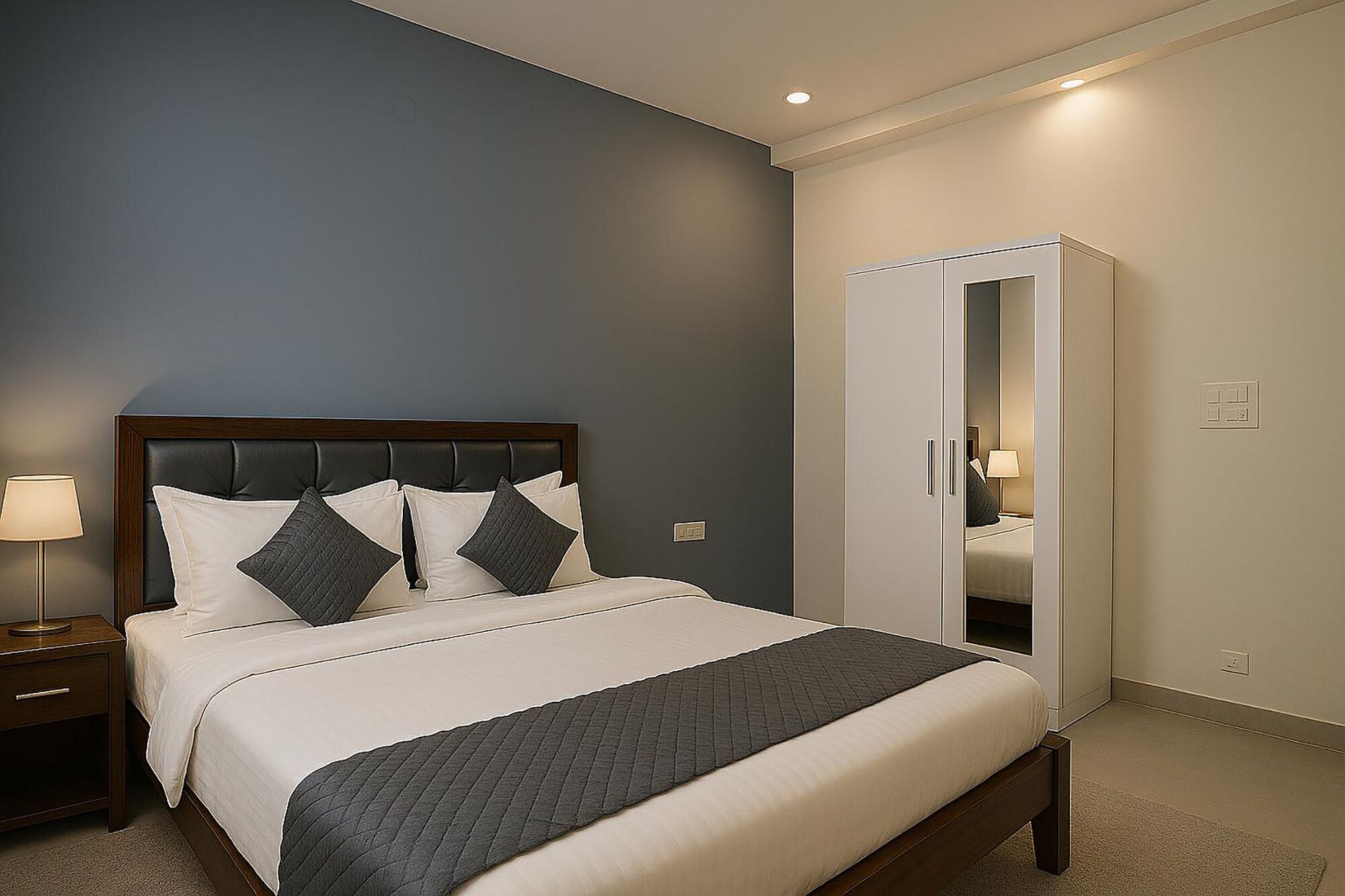 A neatly made bed with a dark headboard, a bedside lamp, and a wardrobe with a mirror.