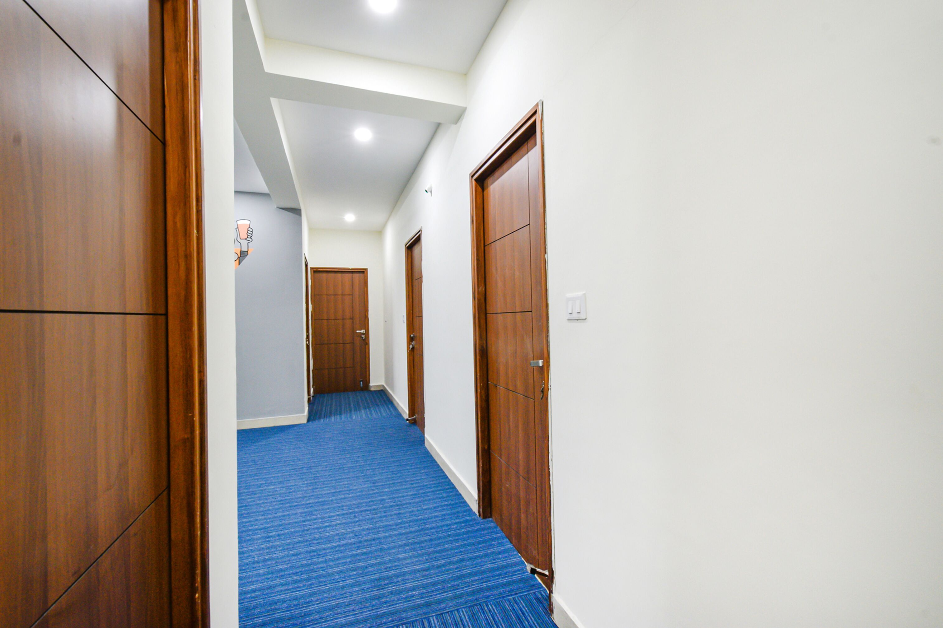 A hallway with wooden doors and a blue carpet.