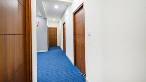 A hallway with wooden doors and a blue carpet. - Fabhotel Maski Suites (Hyderabad)