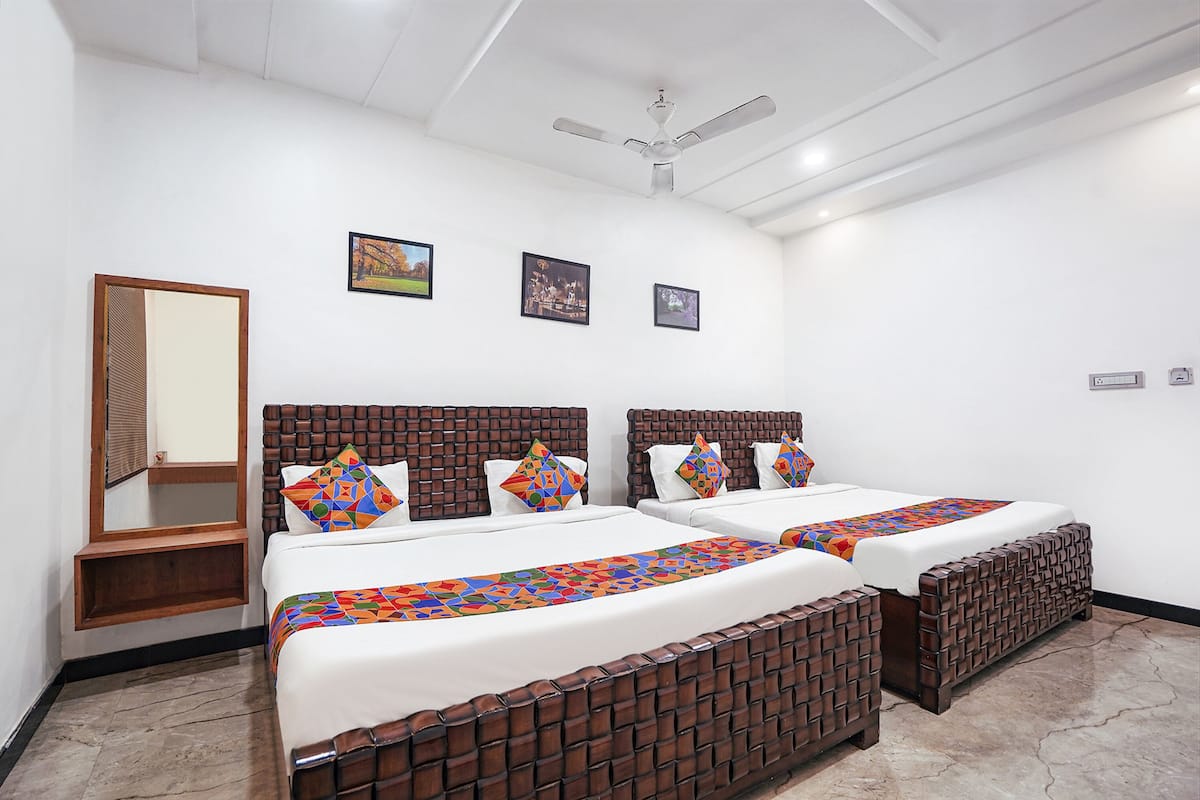 Habitación de hotel con dos camas, un ventilador de techo y tres cuadros en la pared.