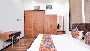 Un dormitorio con un armario de madera, un escritorio y una cama con almohadas de colores.