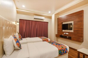 A hotel room with two beds, a TV mounted on a wooden panel, an air conditioning unit, and a window with curtains. - FabHotel Prime The Vintage Inn - Hosur Road (Bengaluru)
