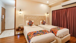A hotel room with two beds, a wooden floor, a large mirror, and an air conditioning unit. - FabHotel Prime The Vintage Inn - Hosur Road (Bengaluru)