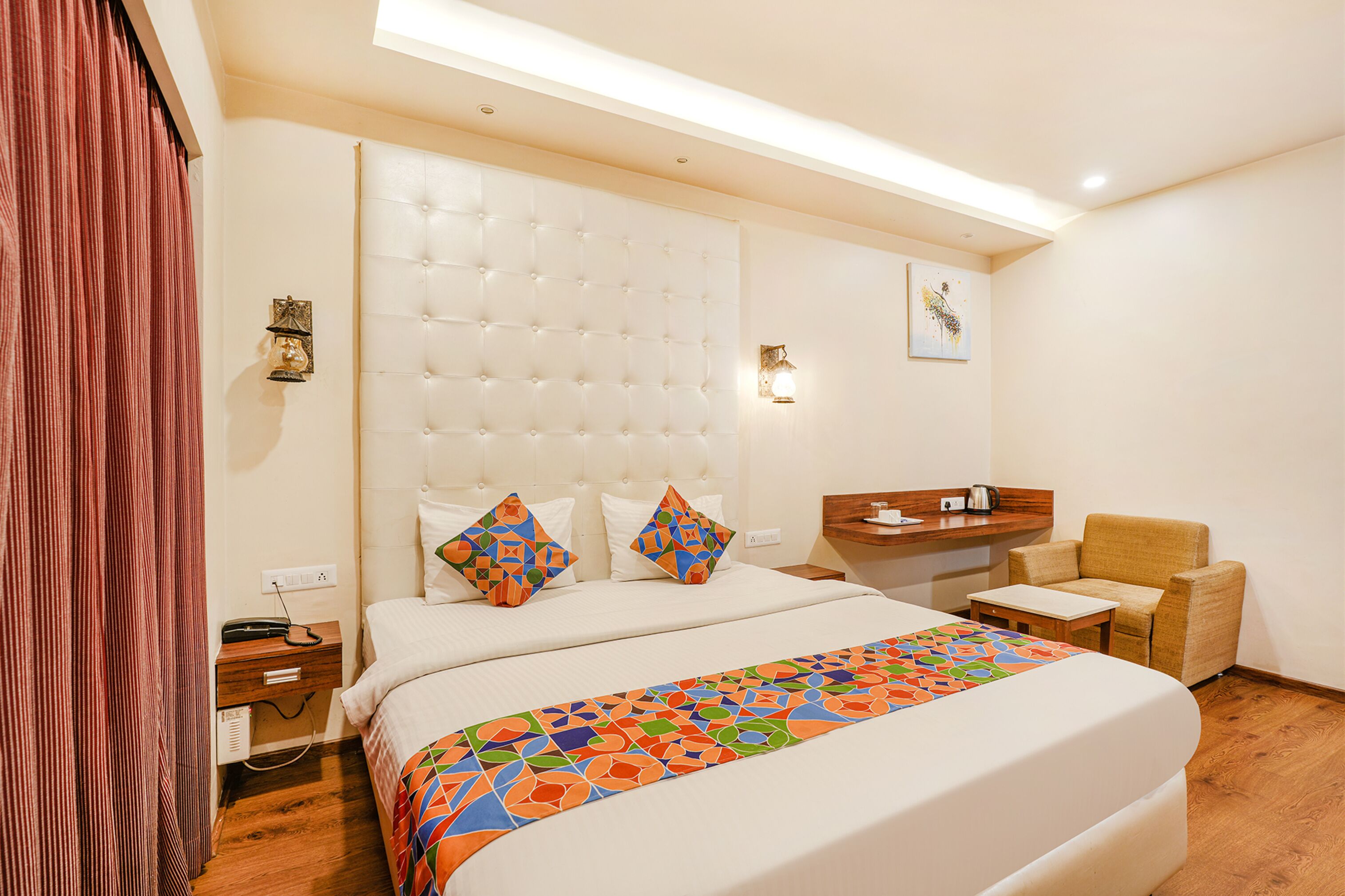 A hotel room with a large bed, a desk, a chair, and a window.