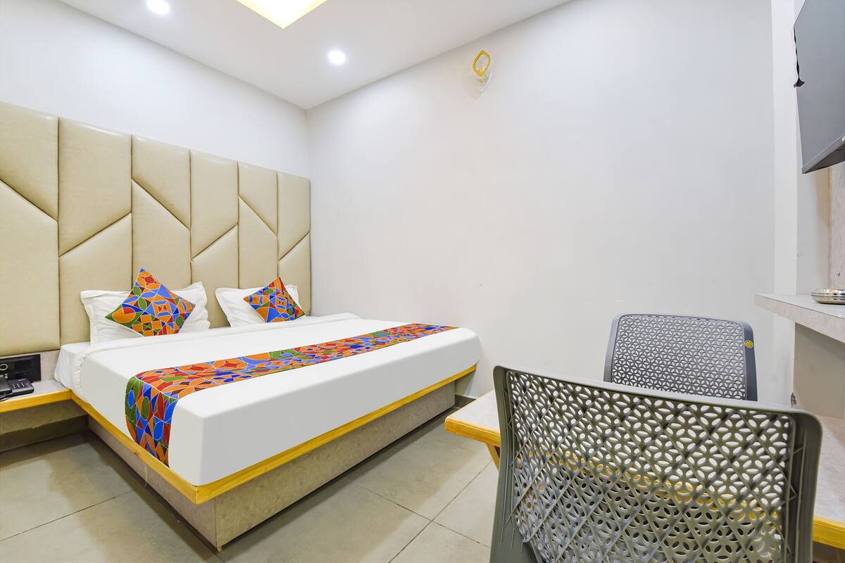 A hotel room with a bed, a chair, a desk, and a television.