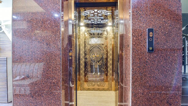 An elevator with a digital display, ornate design, and a marble wall. - Fabhotel Heaven Palace (Haridwar)