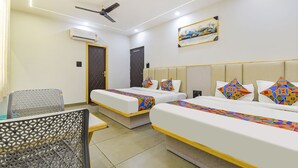 A hotel room with two beds, a ceiling fan, an air conditioner, and a painting on the wall. - Fabhotel Heaven Palace (Haridwar)
