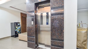 An elevator with a modern design, flanked by marble walls and a tiled floor. - Fabhotel Seri (Hyderabad)