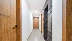 A hallway with wooden doors and a marble wall. - Fabhotel Seri (Hyderabad)