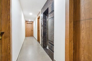 A hallway with wooden doors and a marble wall. - Fabhotel Seri (Hyderabad)